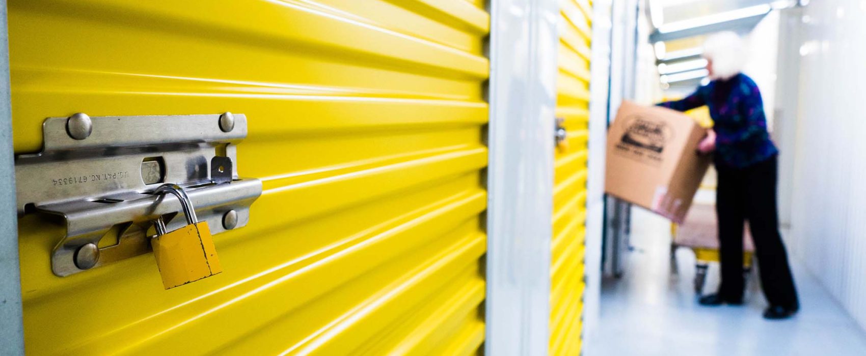 Padlocked storage unit and a worker carrying a box – storage for international removals
