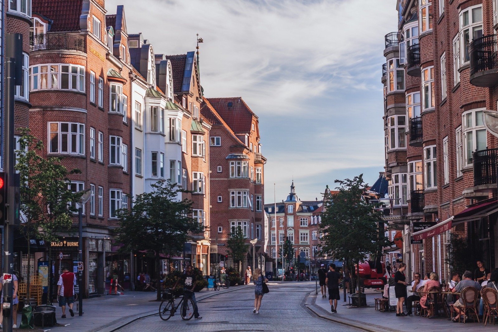 Brick apartment buildings and pedestrians on a street in Aalborg – removals from the UK to Aalborg