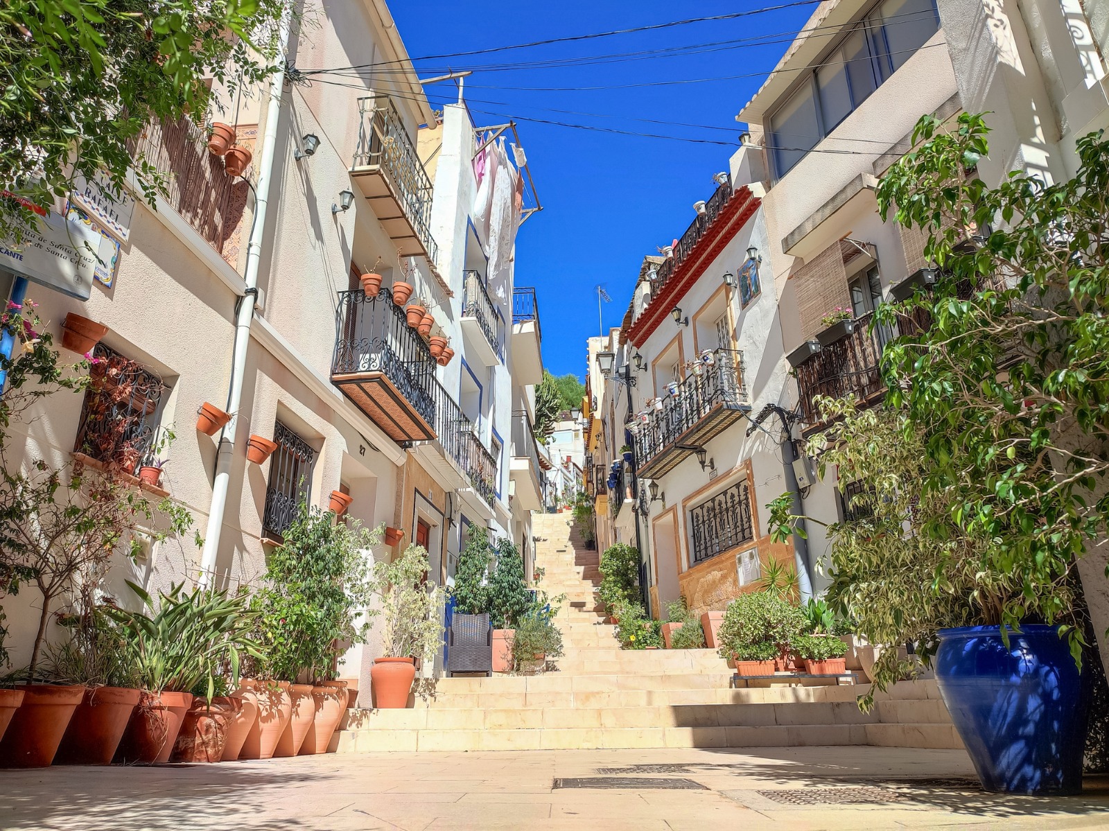 Whitewashed houses and flowers along a stepped lane in Alicante – part-load removals to Alicante