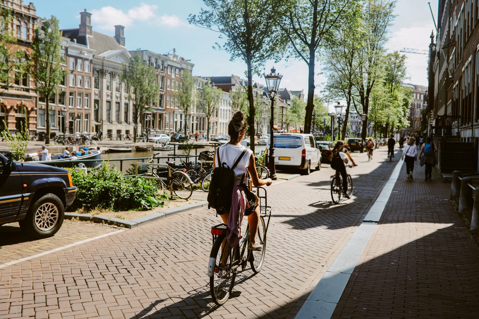 Cyclists on a cobbled street beside a canal in Amsterdam – shared-load removals to Amsterdam
