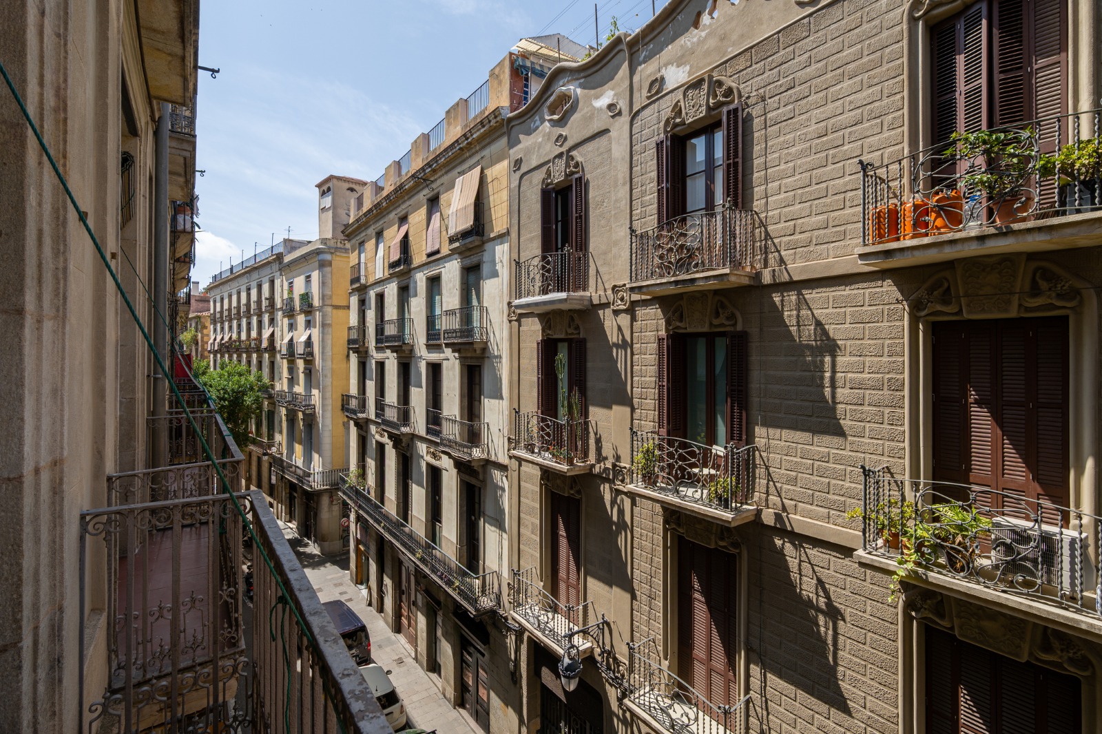Balconies and shuttered windows above a narrow street in Barcelona – moving from the UK to Barcelona