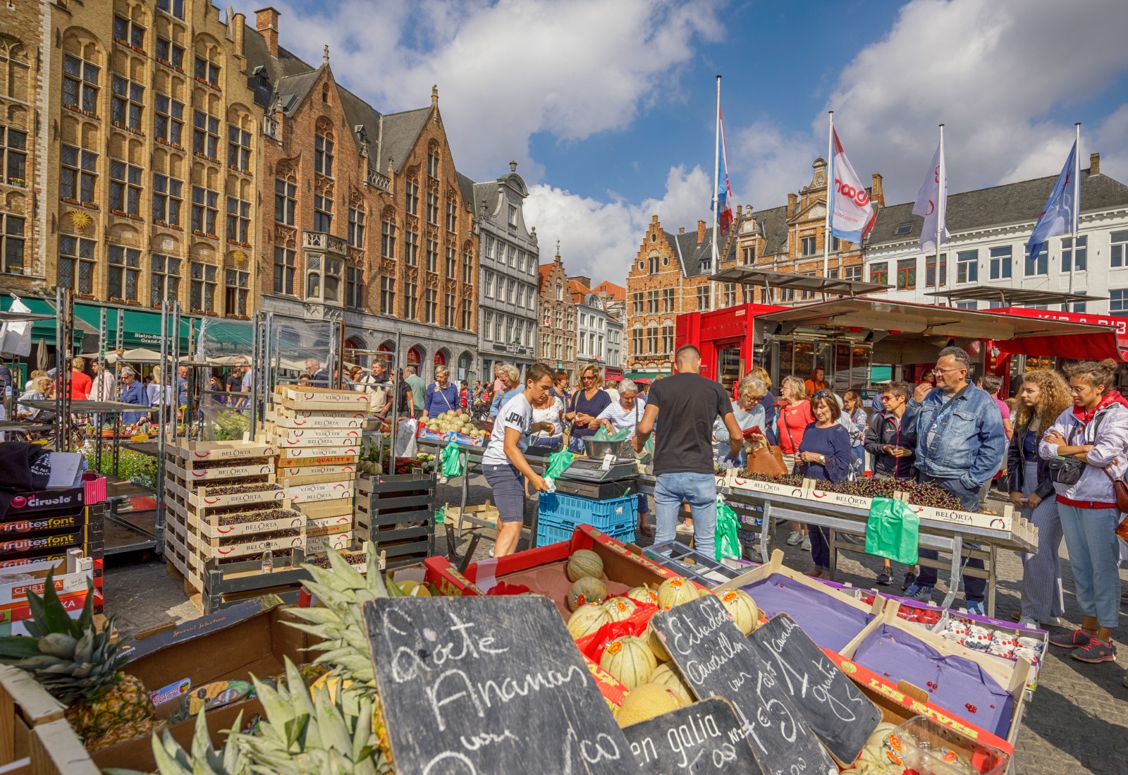 Market stalls and shoppers in a historic square in Bruges – shared-load removals to Bruges