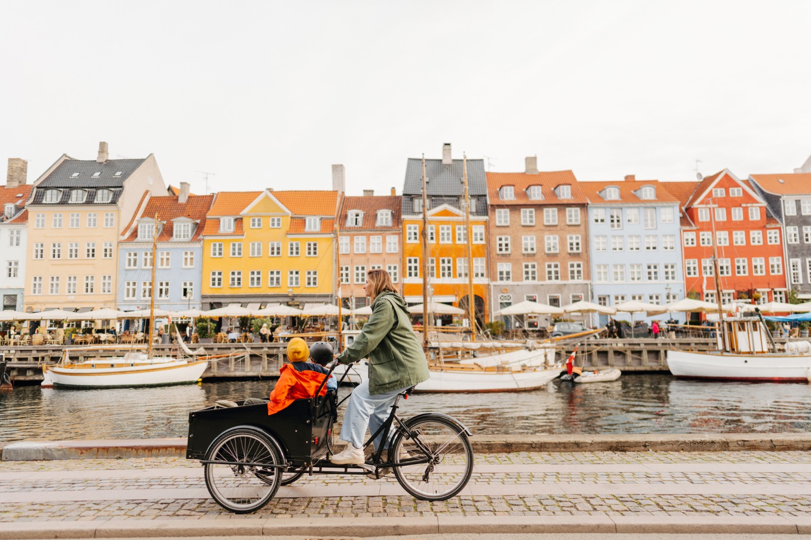 Cyclist passing the colourful waterfront houses of Nyhavn in Copenhagen – moving from the UK to Copenhagen