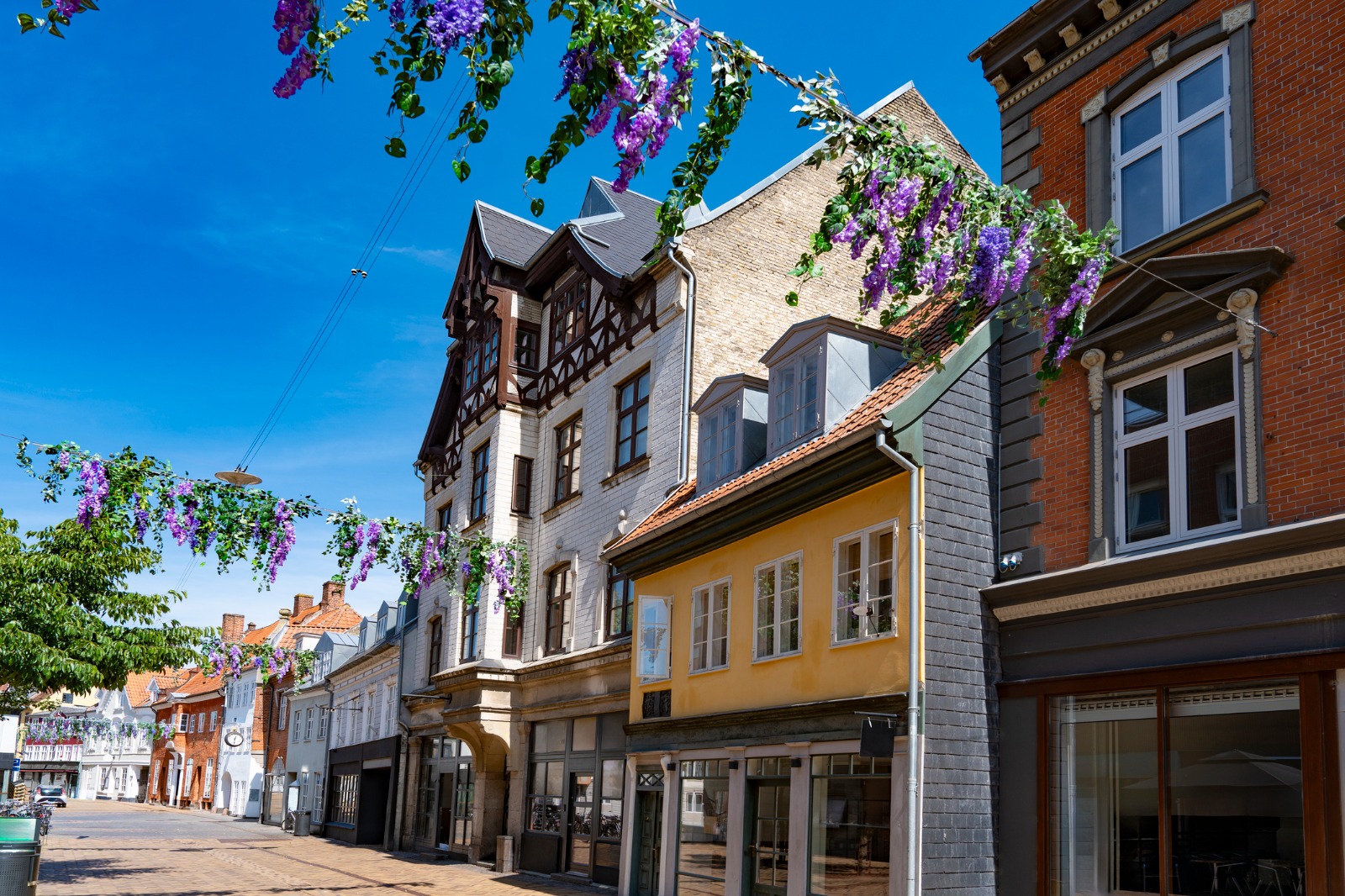 Shops and colourful facades on a street in Odense – shared-load removals to Odense