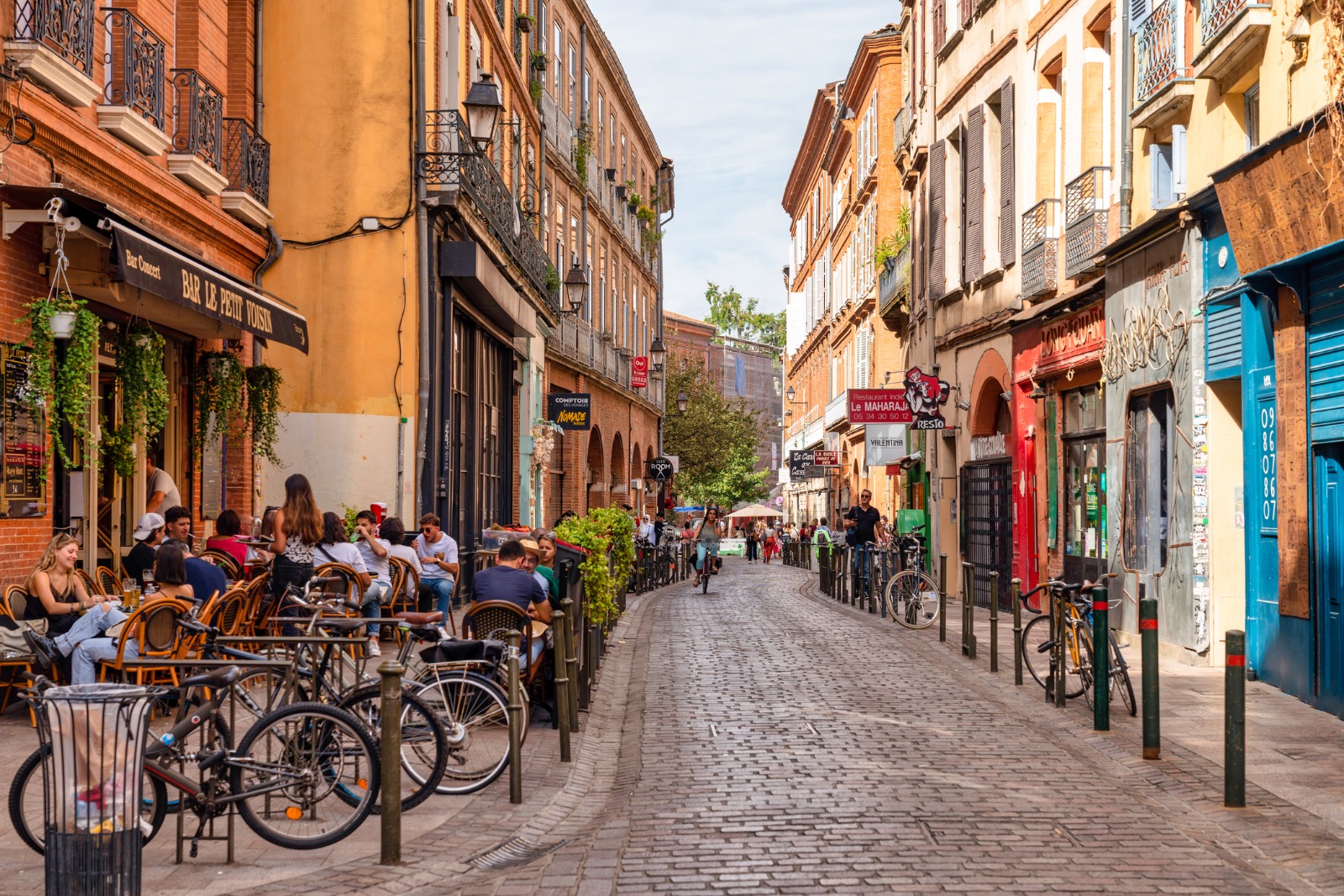 Outdoor cafes and bicycles on a narrow street in Toulouse – moving from the UK to Toulouse
