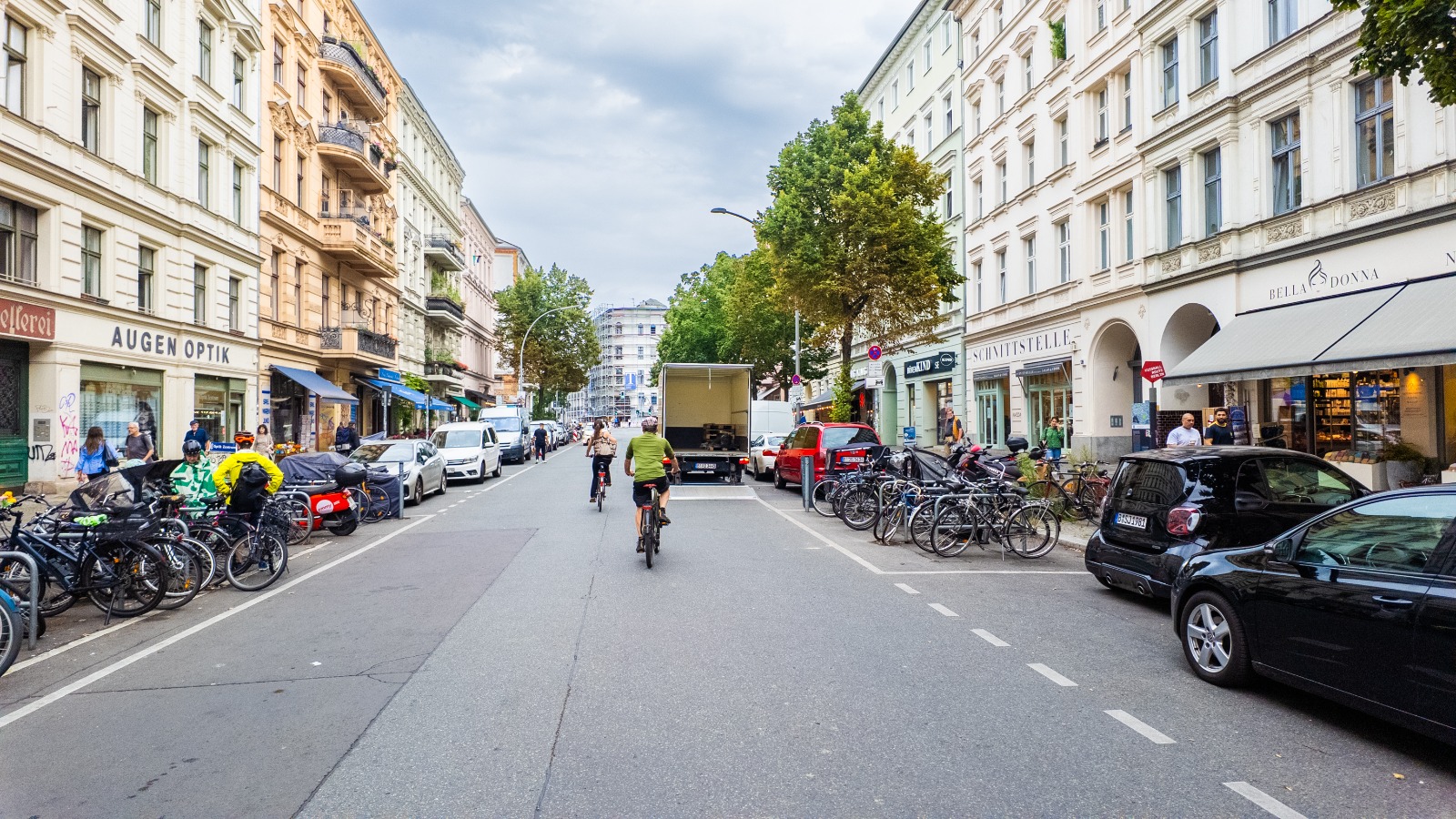 Cyclists and parked cars on a tree-lined street in Berlin – moving from the UK to Berlin
