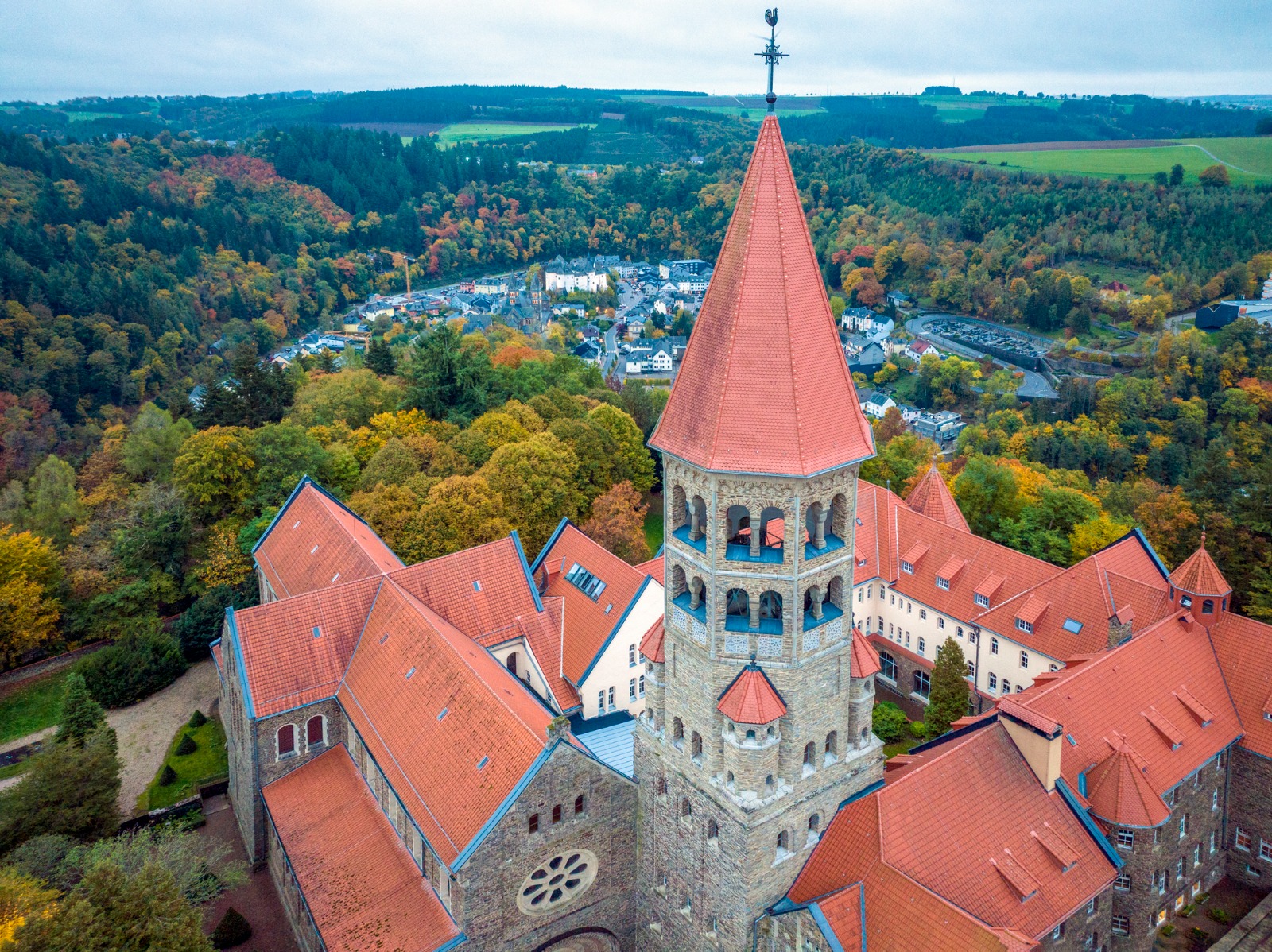 Red-roofed church tower with wooded hills behind in Luxembourg – removals from the UK to Luxembourg