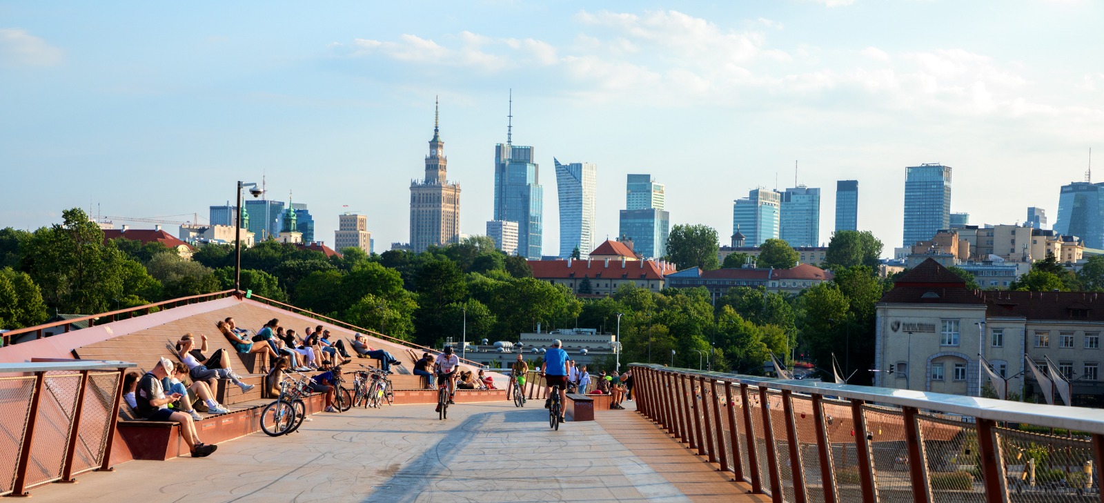 Pedestrians on a footbridge with the Warsaw skyline behind – dedicated removals from the UK to Poland