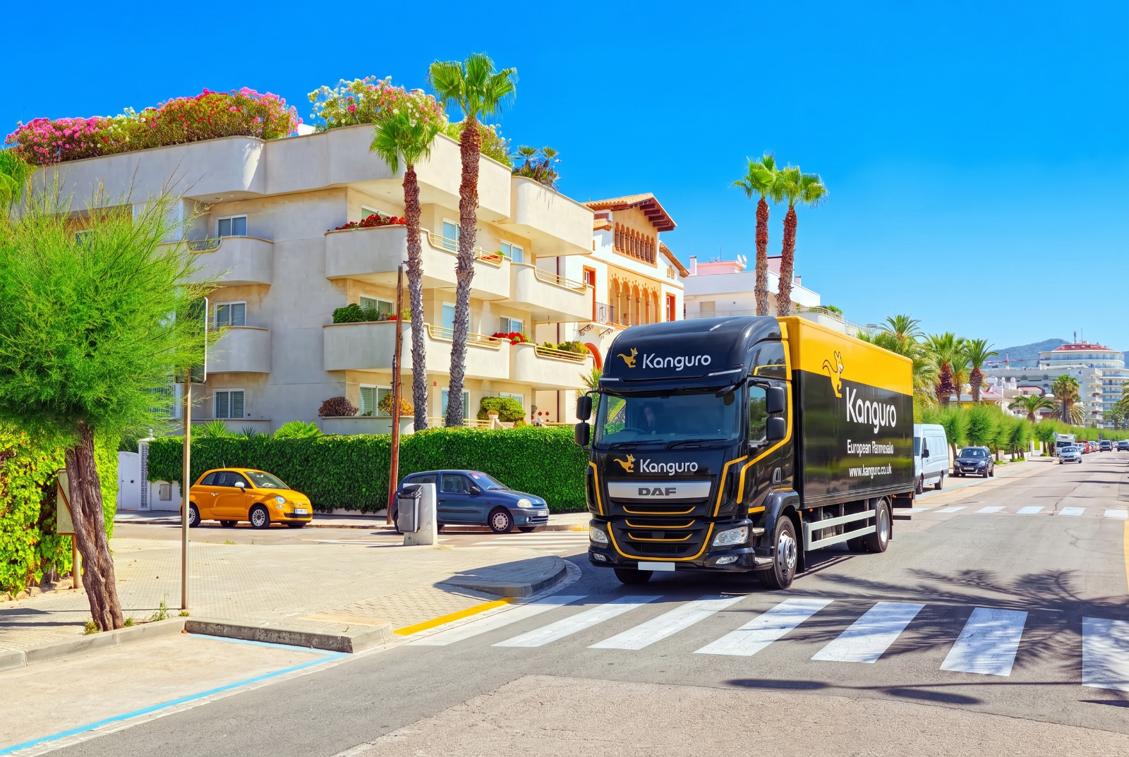 Kanguro removal truck beside palm trees and apartments in Spain – moving from the UK to Spain