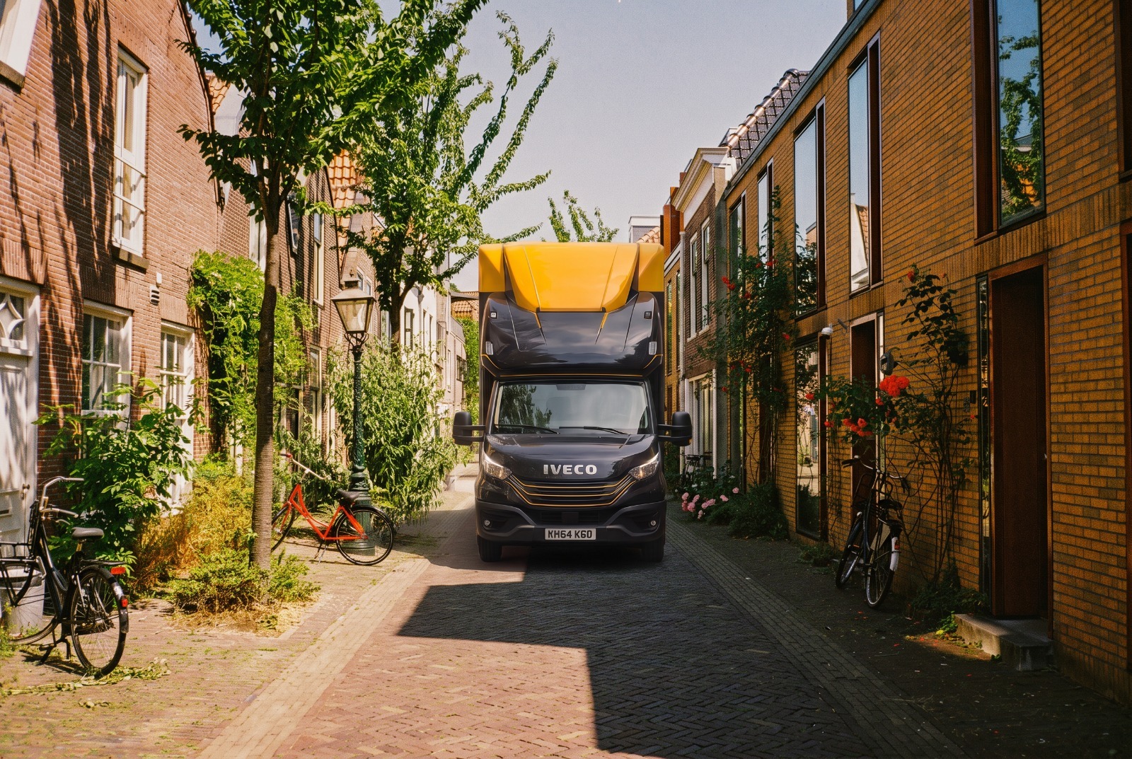 Kanguro removal truck on a narrow residential lane with brick houses – shared-load removals to Europe